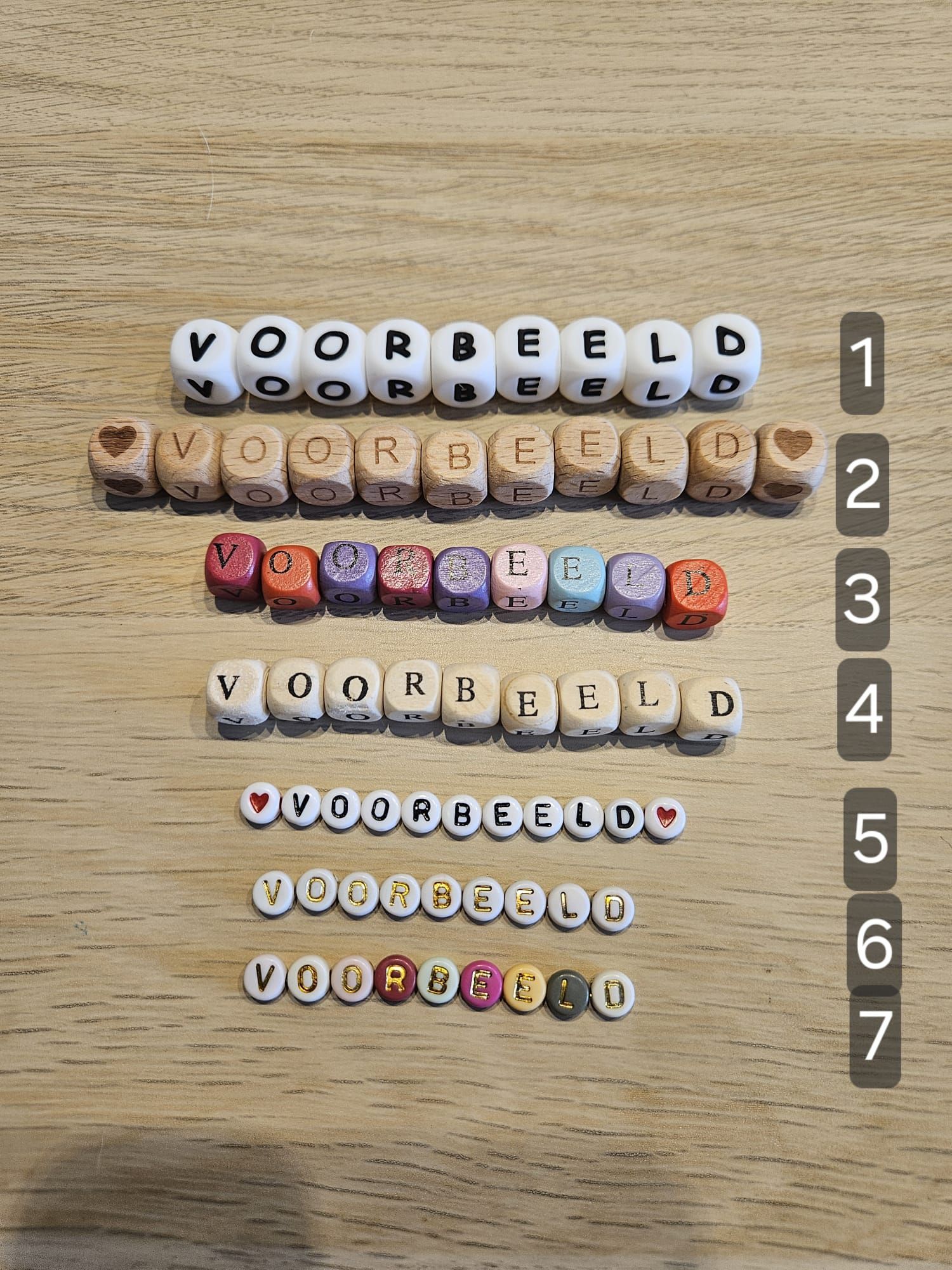 Gekleurde kralen met letters erop, gerangschikt in 7 rijen met labels op een houten tafel; de bovenste rij spelt 