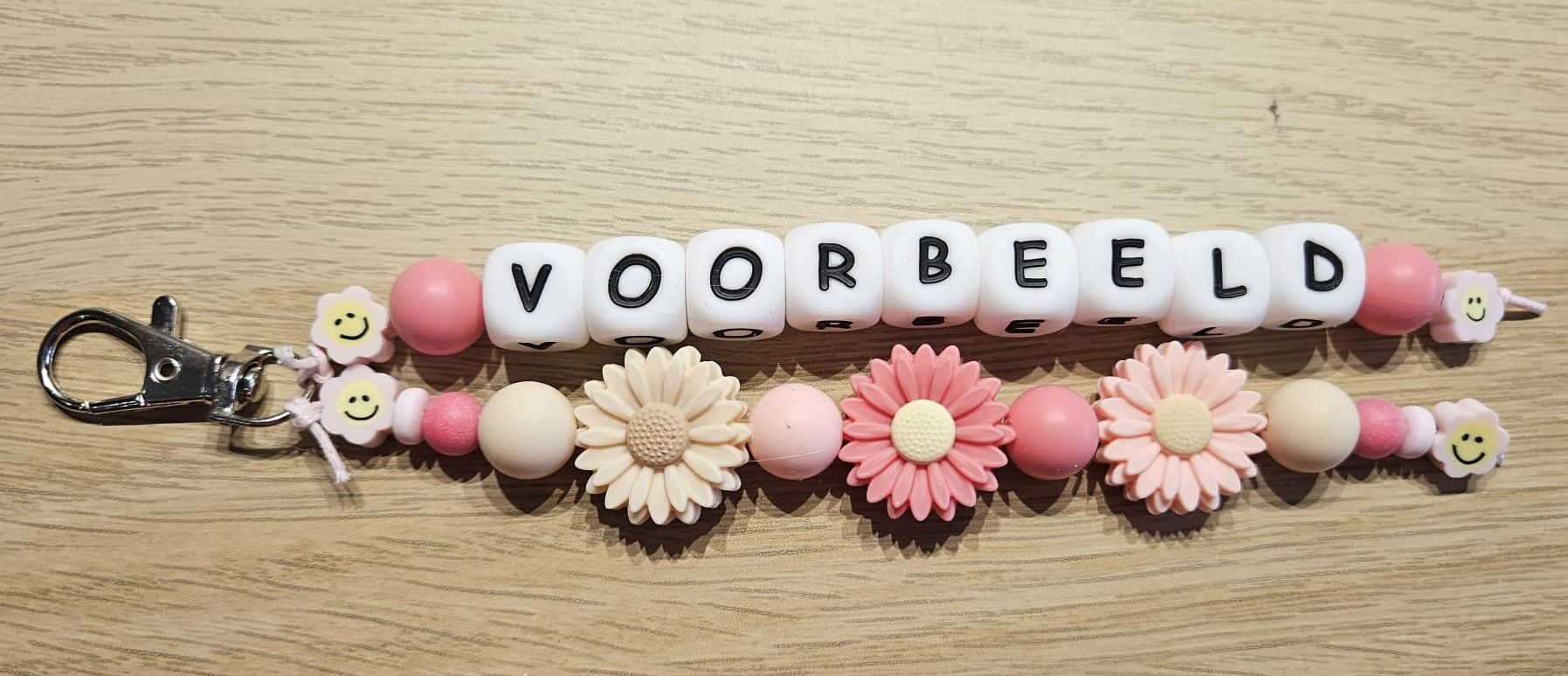 Sleutelhangertje met kralen, roze bloemen en witte letterkralen die samen 