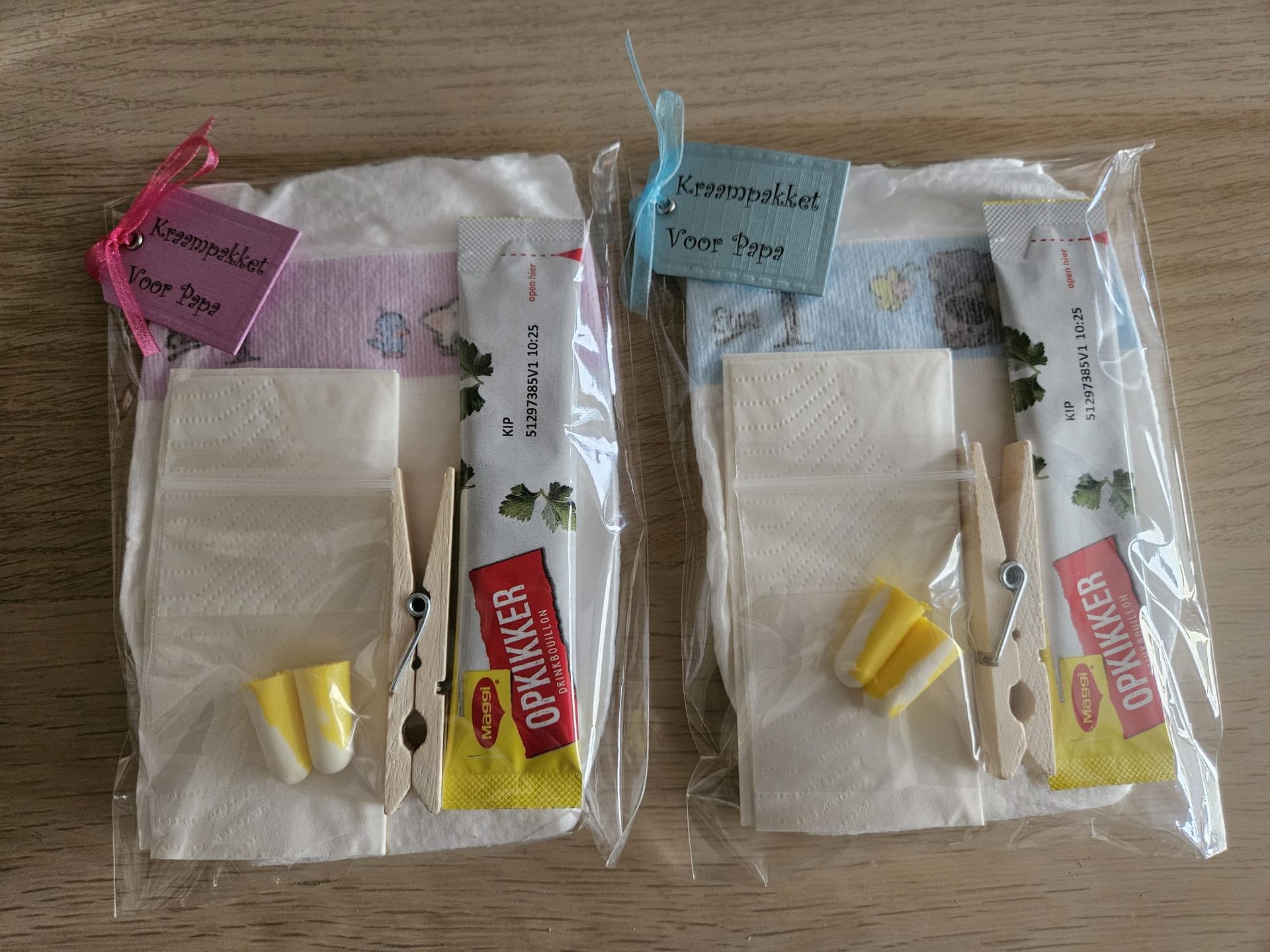 Twee kleine, doorzichtige cadeautasjes met lintjes, vloeipapier en chocoladerepen op een witte ondergrond.