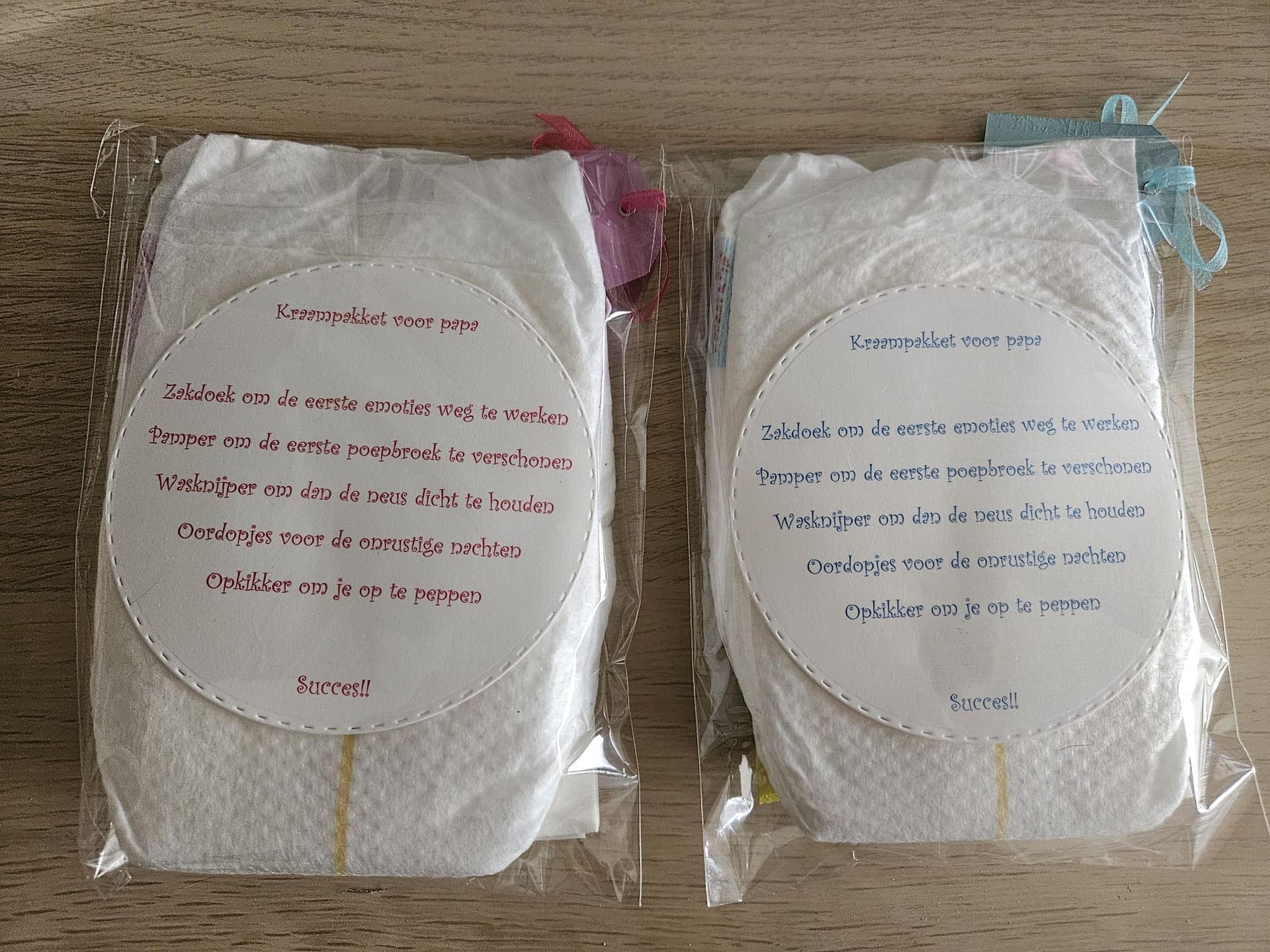Twee ingepakte pakketjes met ovale etiketten, een rode en een blauwe, vastgebonden met touw op een houten ondergrond.