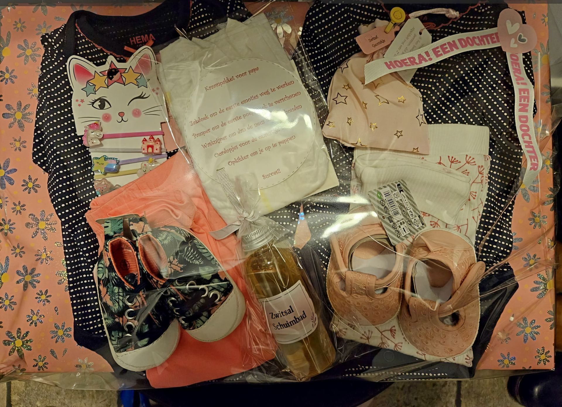 Diverse kledingstukken en accessoires uitgestald op een mat met stippen, waaronder tassen, schoenen en opgevouwen kledingstukken.