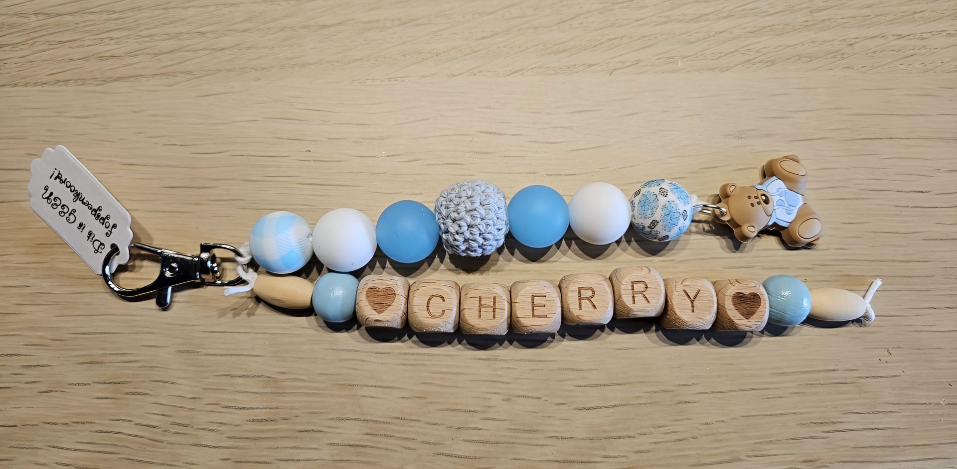 Blauw-witte kralen sleutelhanger met houten letterblokjes die 