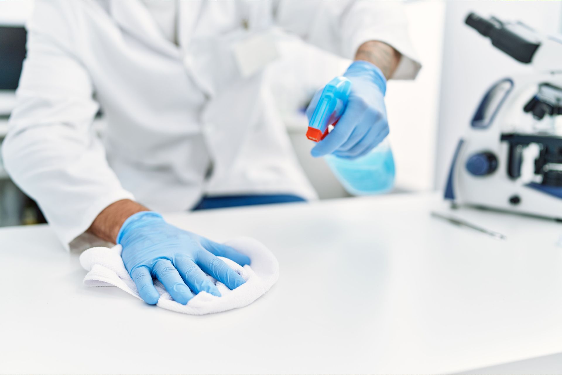 a man is cleaning a table with a cloth and spraying disinfectant