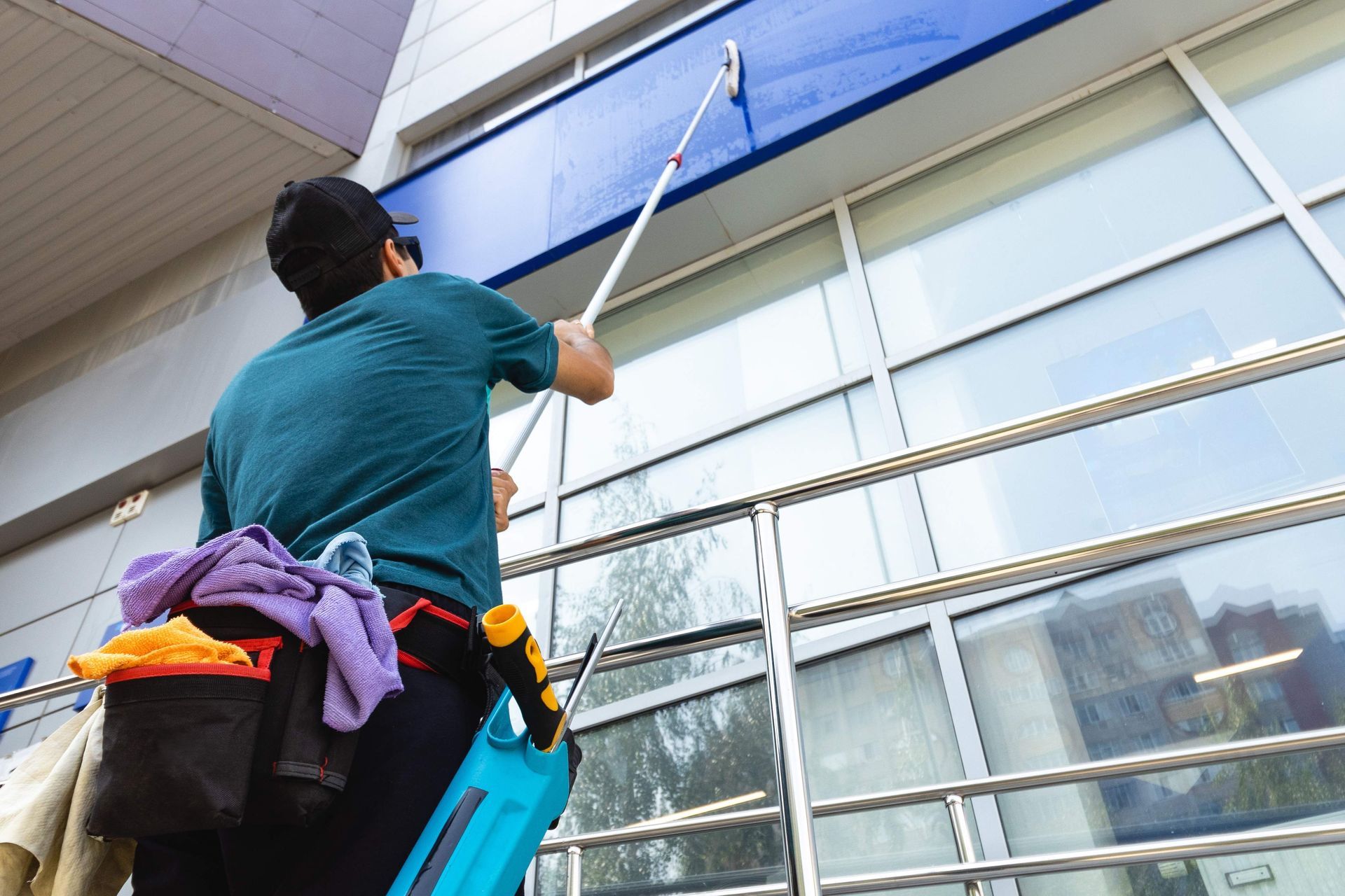 a man is cleaning the windows of a building with a mop