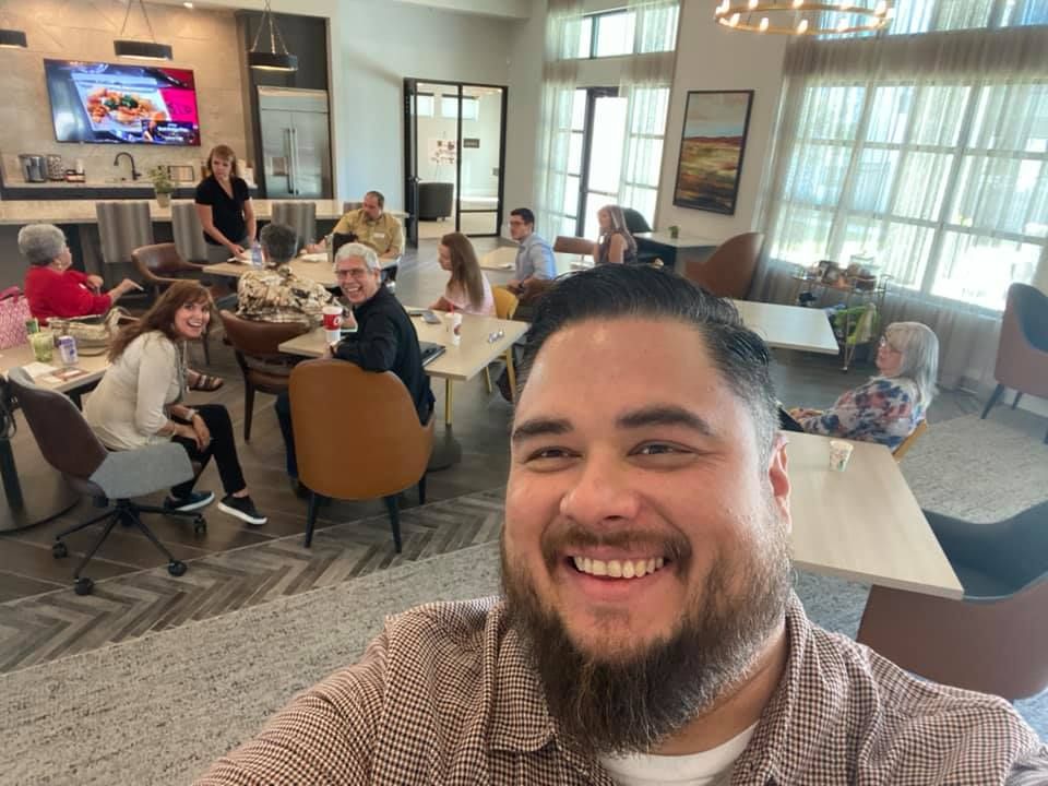 Benbrook Business Exchange A man takes a selfie in a restaurant with a group of people sitting at tables.