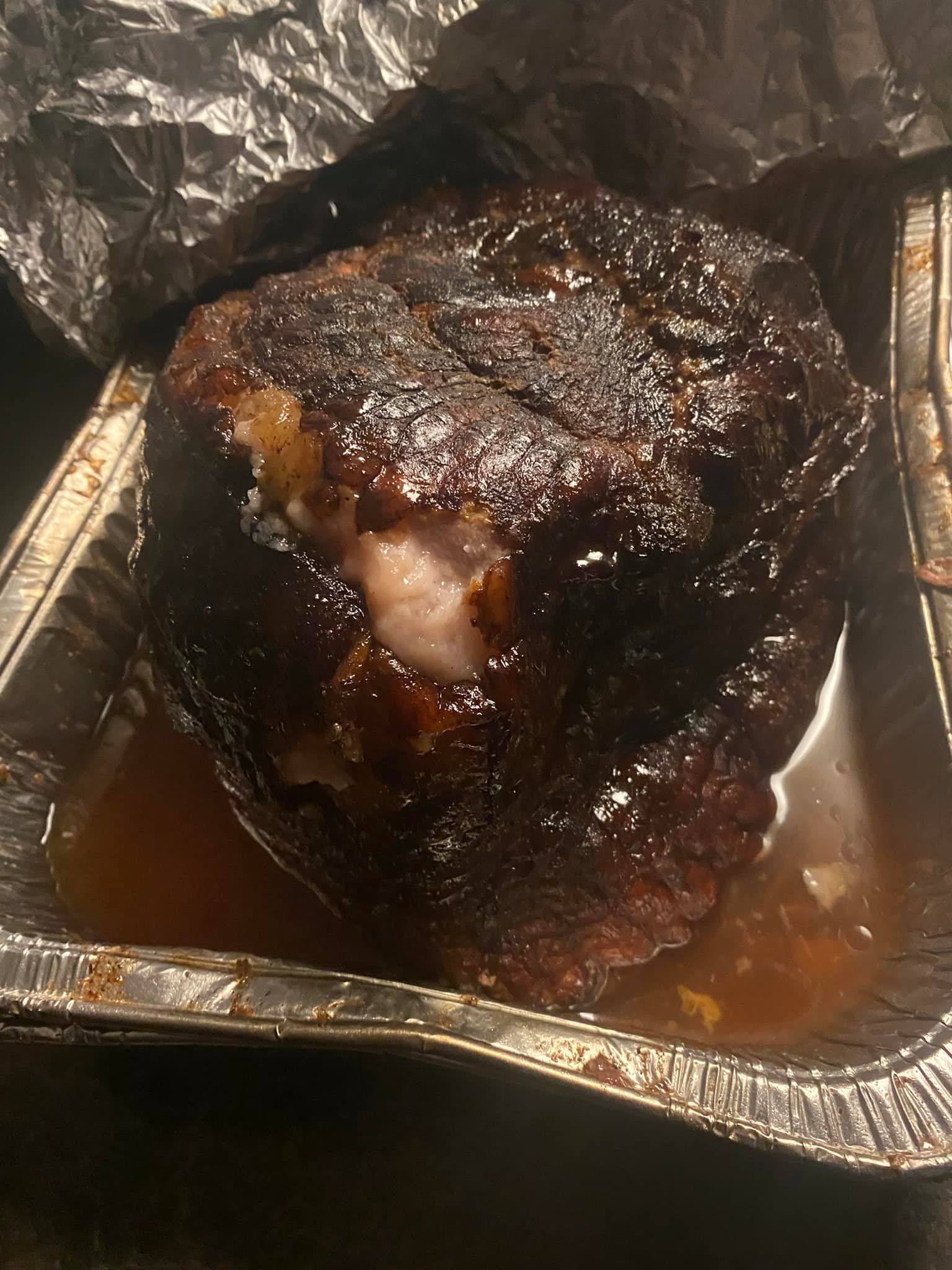 A close up of a piece of meat in a tin foil container.