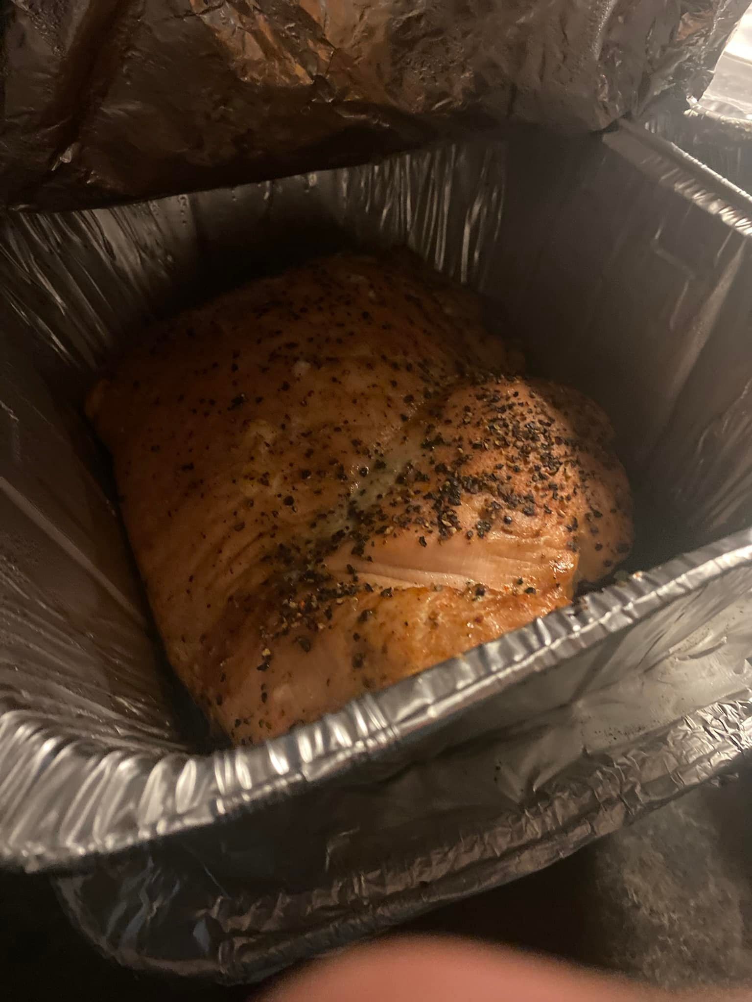 A piece of meat is sitting in a tin foil container.