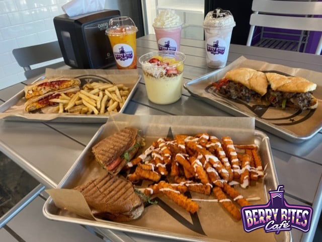 Several trays of food are on a table at the berry bites cafe