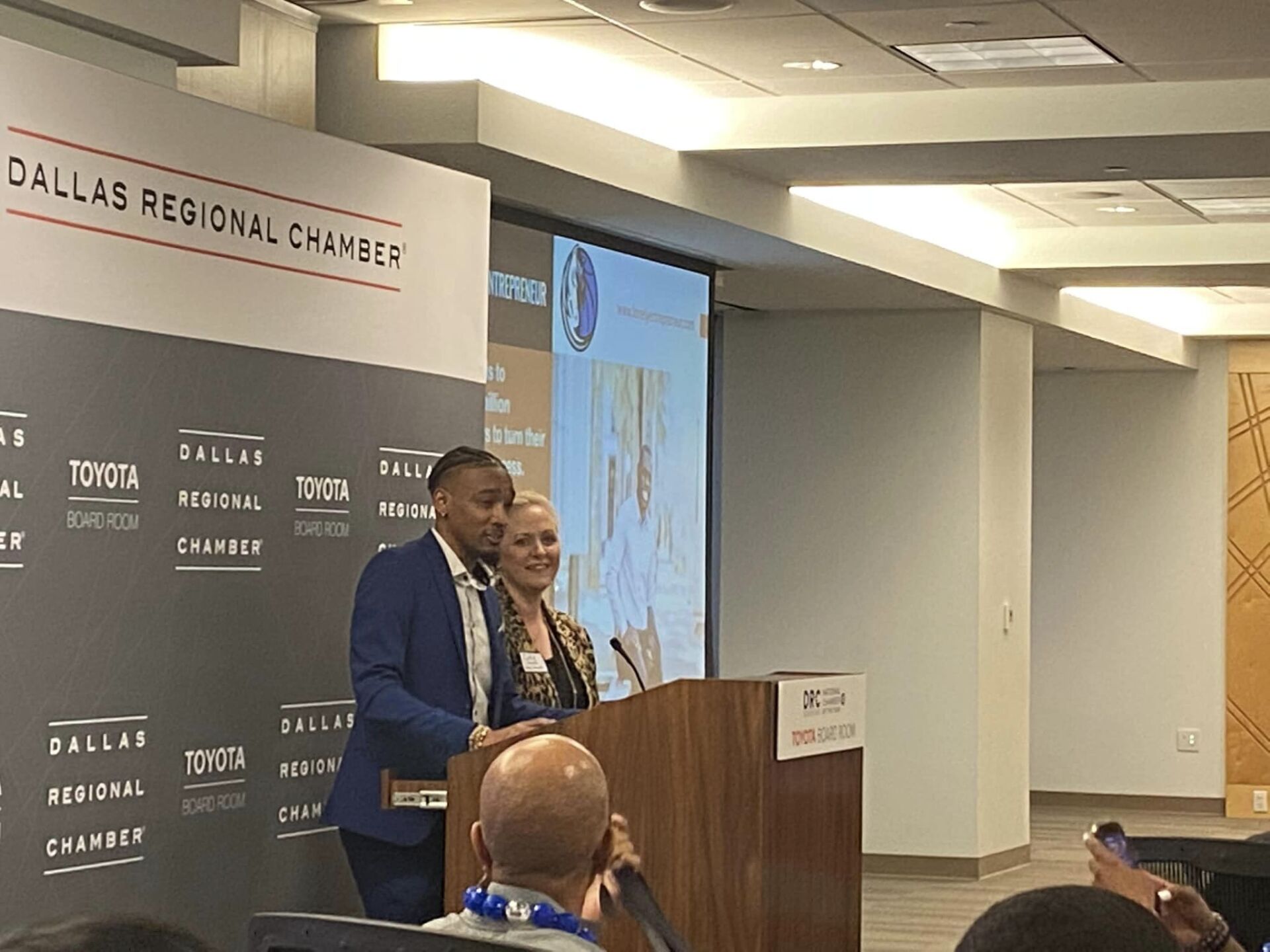 A man and woman are standing at a podium giving a presentation.