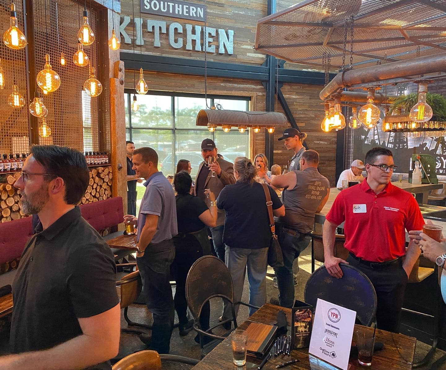 A group of people are standing around tables in a restaurant.