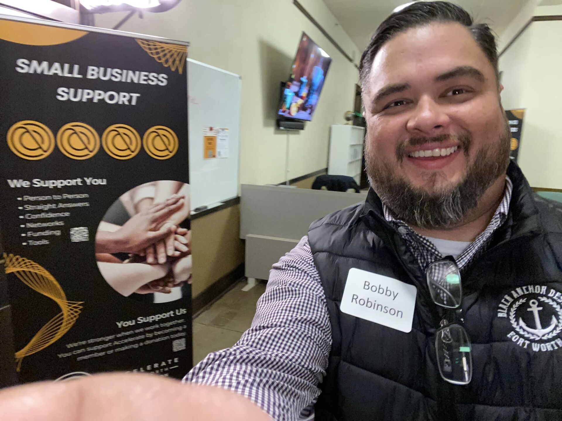 A man with a beard is holding a small business support sign.