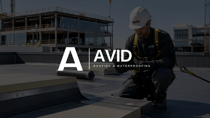 Worker in hard hat kneels on rooftop, inspecting installed roofing layers with AVID logo overlaid.