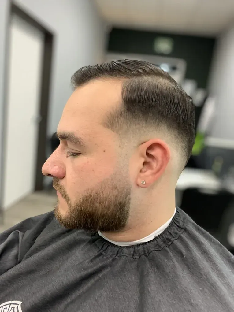 Man with a faded haircut and beard in a barber shop.