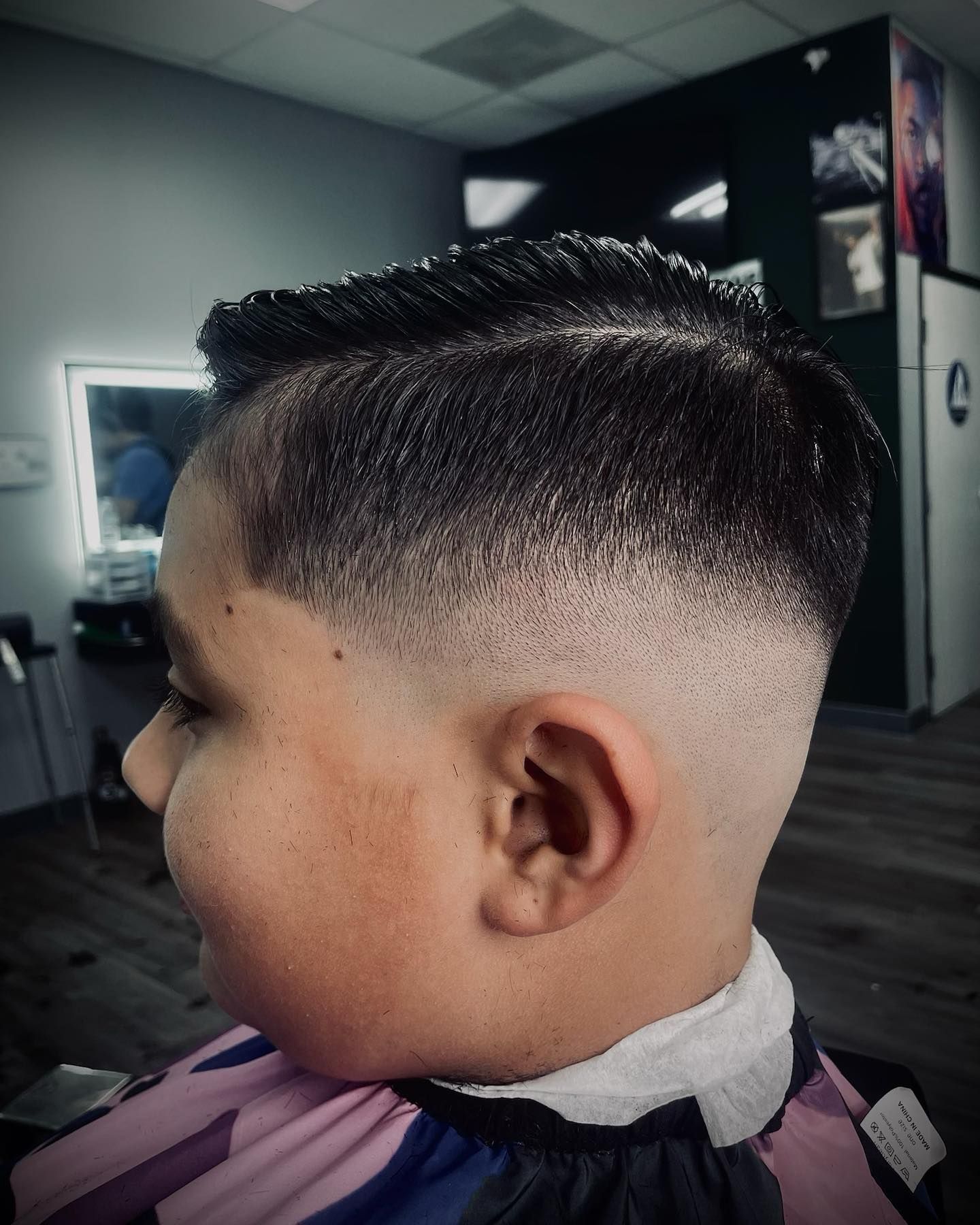Boy with a faded haircut at a barbershop, hair styled to the side.