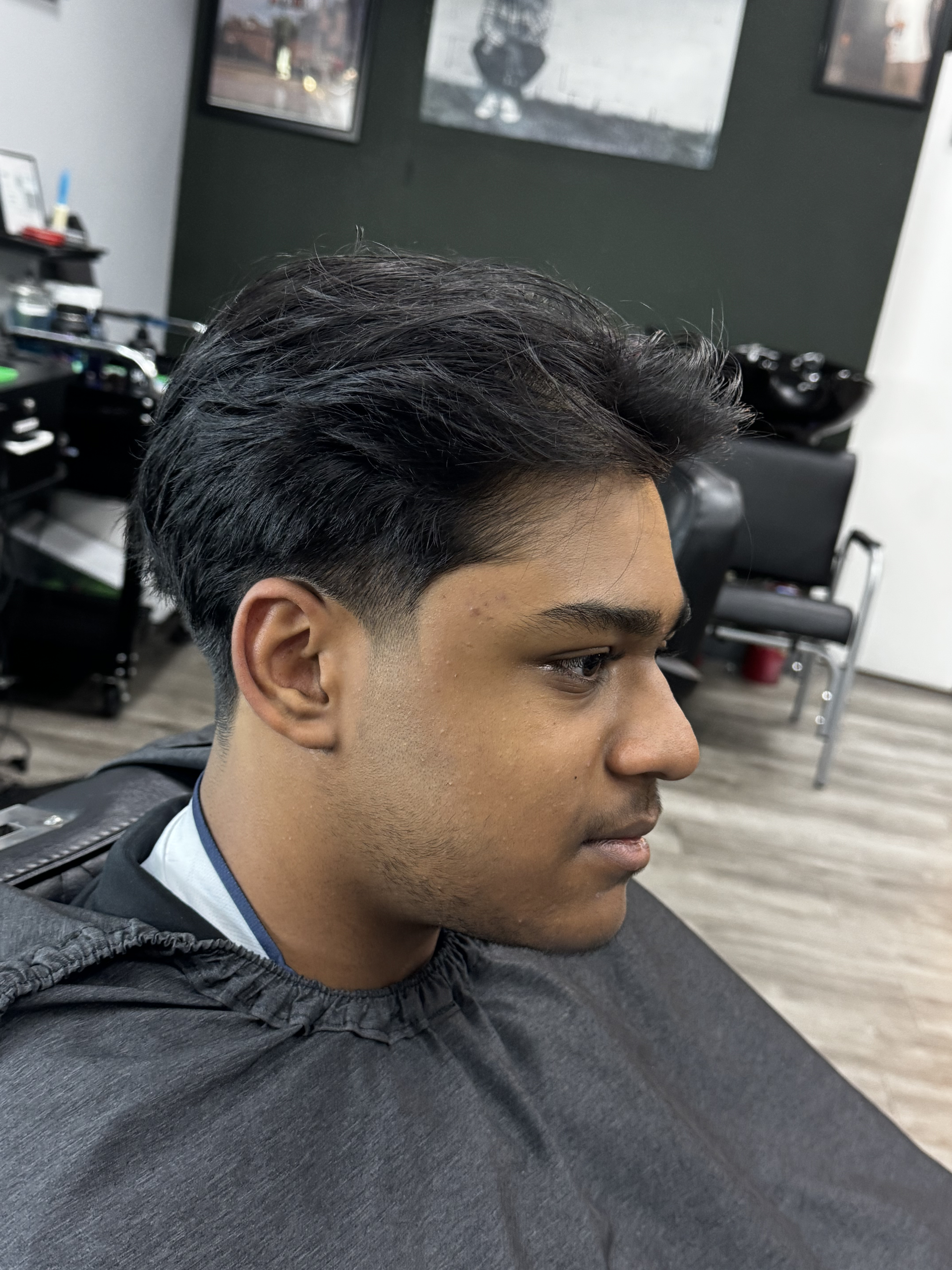 Man with a fresh haircut at a barbershop, showcasing a low fade.