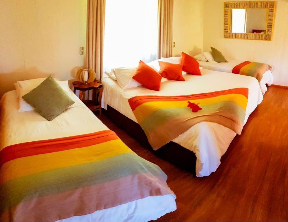 A hotel room with three beds and a mirror