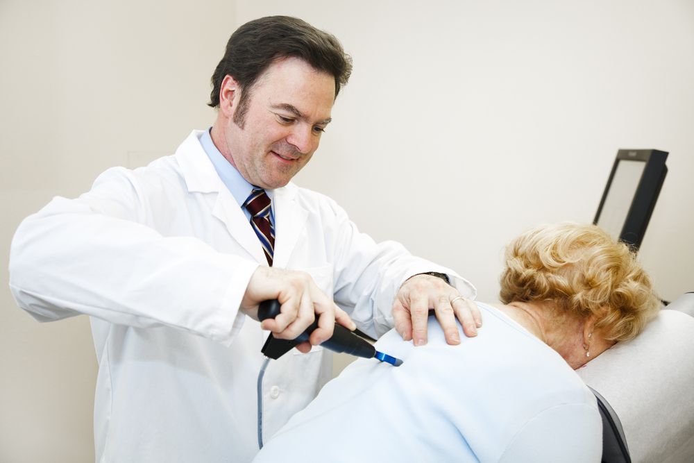 A Person Using a Medical Device on a Patient's Back — Wide Bay Chiropractic in Gympie, QLD
