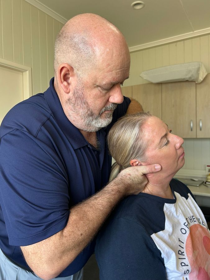 Woman in Blue Shirt Examining a Patient's Neck in a Clinic Setting — Wide Bay Chiropractic in Gympie, QLD