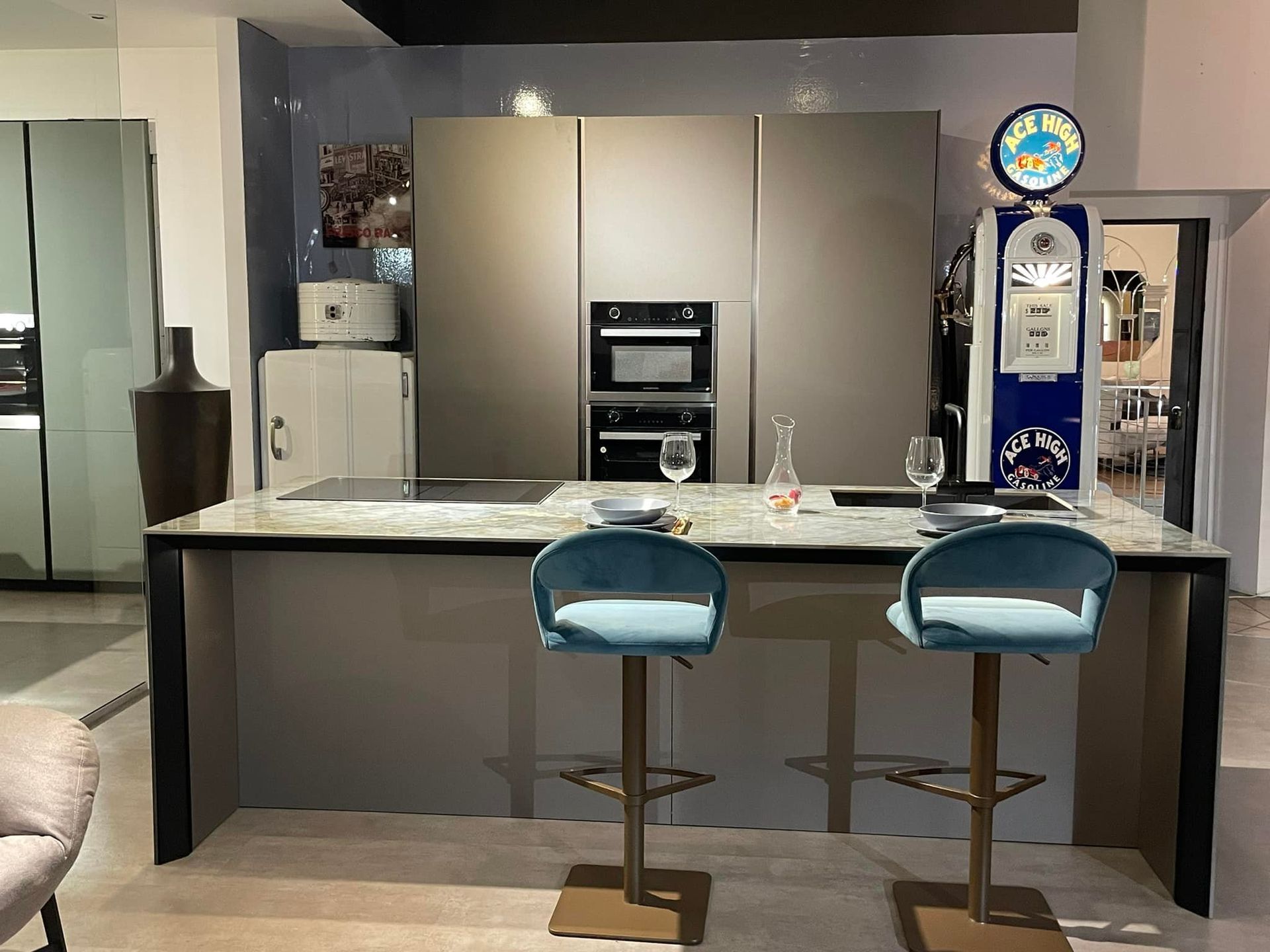 Cucina moderna con mobili in legno chiaro e grigio scuro, elettrodomestici in acciaio inossidabile e tavoli da pranzo.