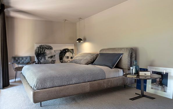 Camera da letto con letto grande, comodino, opere d'arte e toni grigi e neutri.