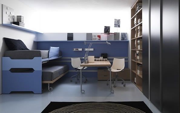 Camera moderna con dettagli in blu, letto a castello, scrivania, sedie e ampio spazio per riporre gli oggetti.