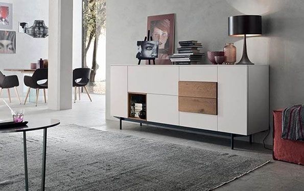 Credenza moderna bianca e in legno con elementi decorativi in ​​un soggiorno con tappeto e lampada.