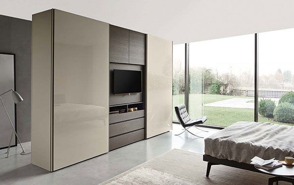 Moderna camera da letto con armadio a muro, TV, letto e ampia finestra con vista sul cortile.