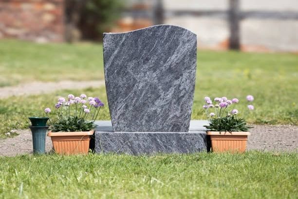 Gravestone with purple flowers in a cemetery lawn