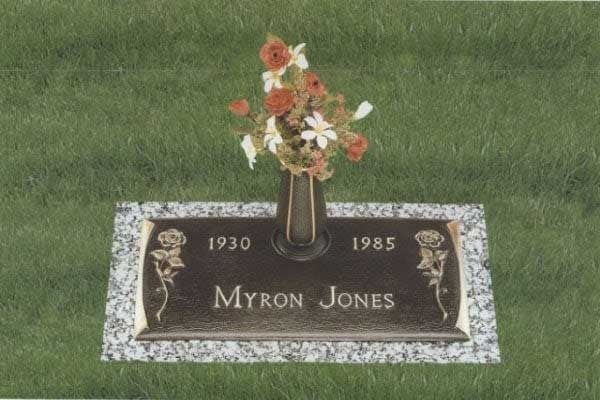 Gravestone for Myron Jones with flowers, showing dates 1930 and 1985 in a grassy cemetery.