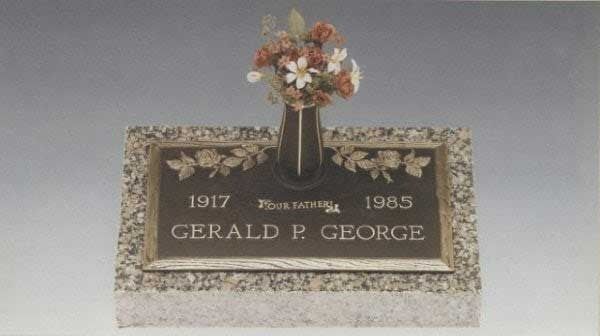 Gravestone for Gerald P. George with floral arrangement, marked 1917 and 1985.