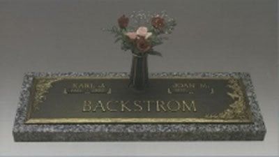 Grave marker with a vase of flowers and the name BACKSTROM on a dark plaque