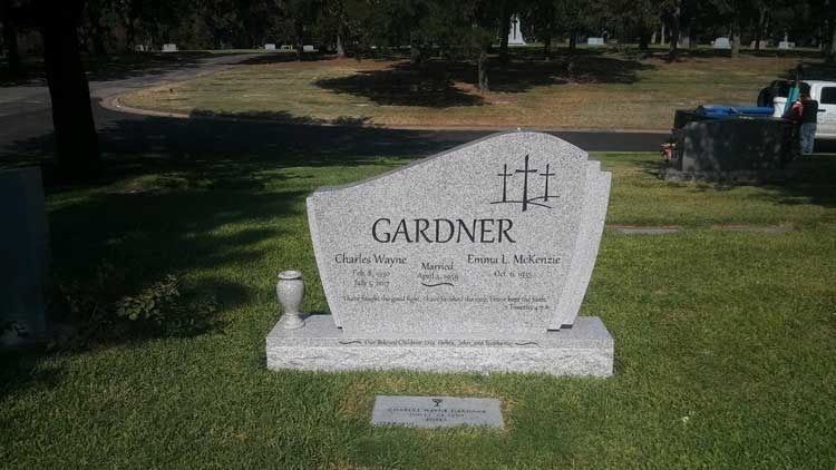 White Gardner gravestone in a grassy cemetery with trees in the background