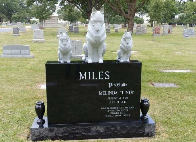 Pet memorial gravestone with three cat statues in a cemetery, including the name “MILES.”