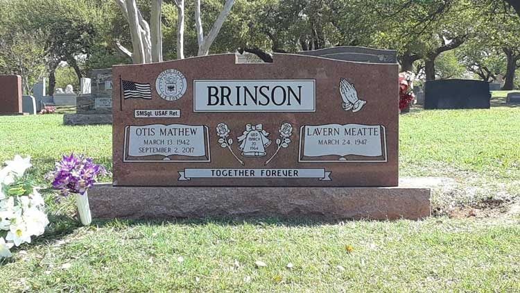 Brinson family gravestone in a grassy cemetery, with flowers beside it.