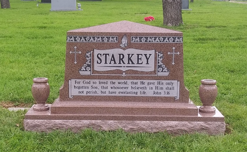 Decorative brown Starkey grave marker in a green cemetery lawn with two small urns on either side