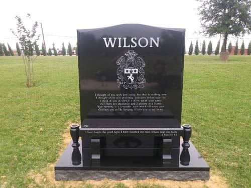 Black granite Wilson gravestone in a grassy cemetery, with white lettering and a framed photo plaque.
