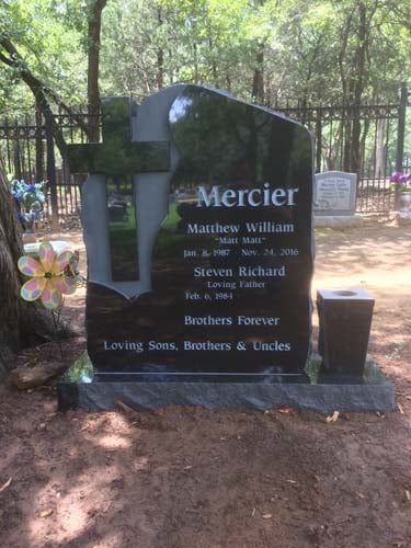 Black headstone with flowers and decorations in a fenced cemetery, honoring the Mercier family