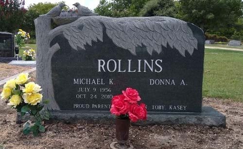 Rolins gravestone with engraved leaves and flowers in a cemetery