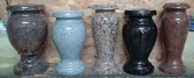 Five decorative urns in gray, light blue, speckled beige, black, and brown lined up on a surface