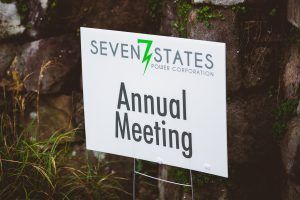 A sign that says seven states annual meeting is sitting in front of a rock wall.