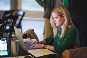 A woman is sitting at a table using a laptop computer.