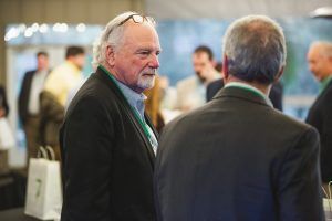 A group of men are standing in a room talking to each other.