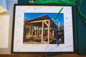 A framed picture of a building under construction with people signing it.