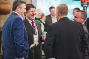A group of men in suits and ties are talking to each other at a conference.