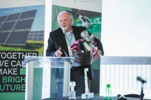 A man is standing at a podium holding a robot arm.