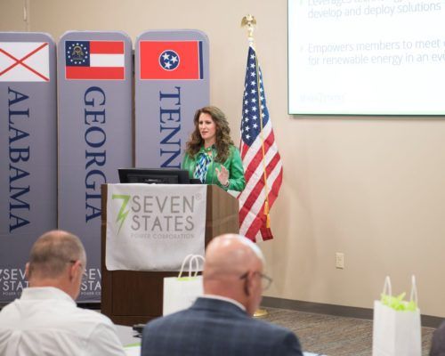 A woman is giving a presentation at a podium that says seven states