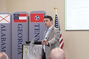 A man is giving a speech in front of a podium that says seven states