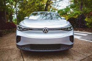 The front end of a silver volkswagen id 4 is parked on a sidewalk.