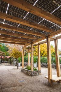 A wooden pergola with solar panels on the roof.