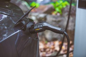 A close up of an electric car being charged at a charging station.